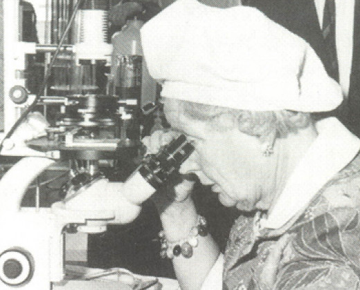 Zwart wit foto met vrouwelijke onderzoeker achter microscoop